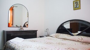 Een slaapkamer met een bed, een dressoir, een spiegel en een foto aan de muur.