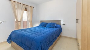 A bedroom with a bed, curtains, a nightstand, and a wardrobe. - APARTMENT IN SANT ANTONI DE CALONGE 17 METERS FROM THE BEACH (Sant Antoni de Calonge)
