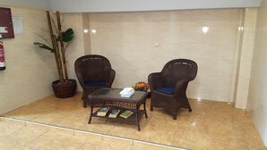 A reception area with two wicker chairs, a glass-top table with a stack of papers, a potted plant, and a fire extinguisher on the wall. - APARTMENT IN SANT ANTONI DE CALONGE 17 METERS FROM THE BEACH (Sant Antoni de Calonge)