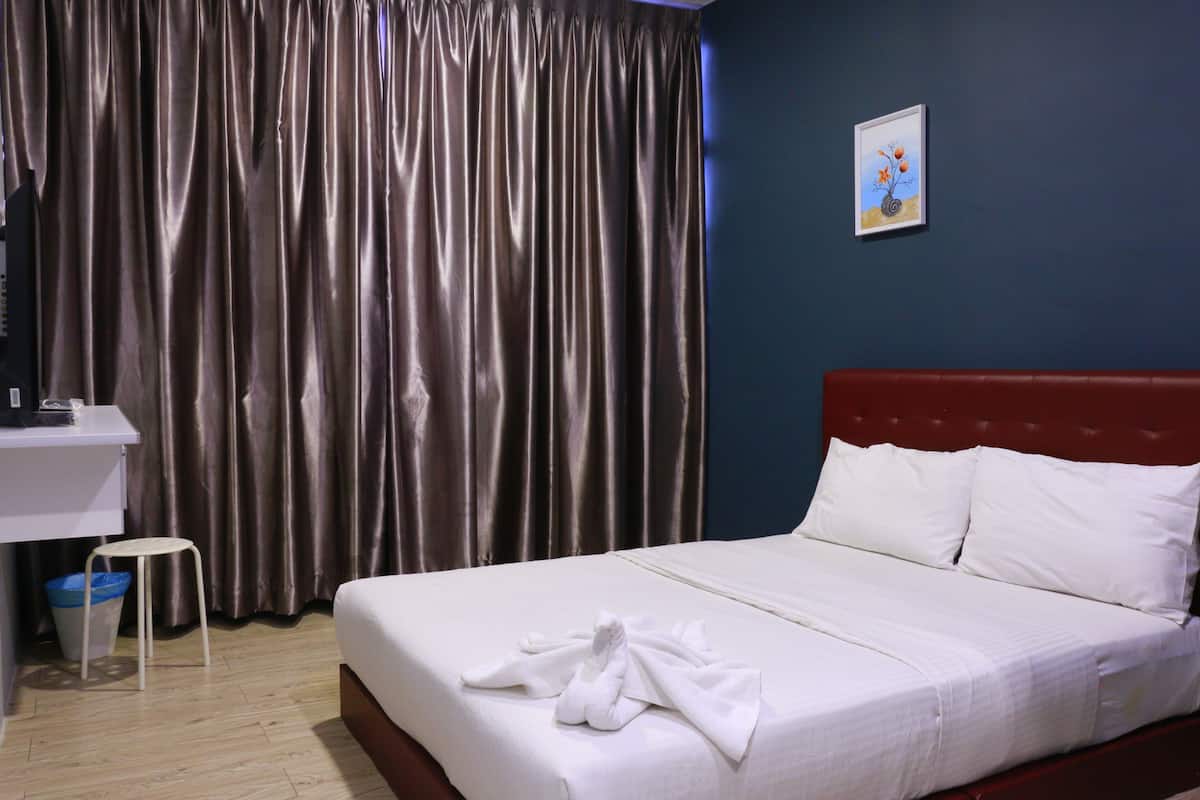 Quarto de hotel com cama, escrivaninha, cadeira, lixeira e um quadro na parede.