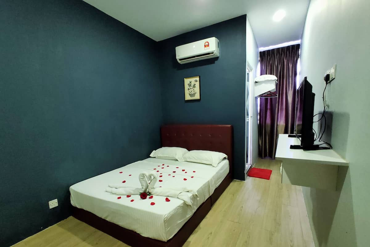 Quarto de hotel com cama, mesa de cabeceira, ar condicionado, televisão e janela com cortinas.
