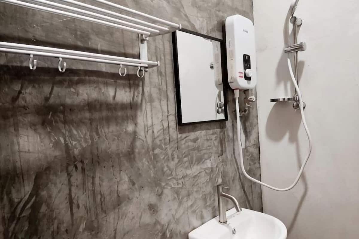 Casa de banho com parede de mármore, um porta-toalhas, uma pia e um chuveiro manual.