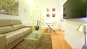 Un salon moderne avec un canapé, une table basse en verre, une plante en pot et un coin repas comprenant des chaises et une table.