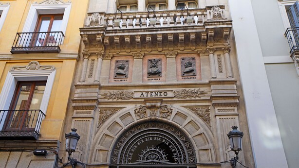 Une façade d’immeuble historique présentant des détails architecturaux élaborés, notamment une entrée en arc en saillie et des plaques décoratives.