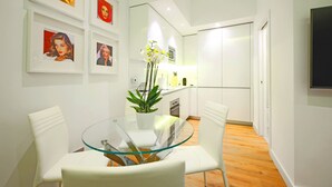 Une cuisine moderne avec des meubles blancs, une table à manger en verre et des chaises blanches.
