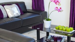 A modern living room with a sofa, a glass coffee table, a potted orchid, and a tray of green apples. - Protaras Villa Hollywood Near To The Centre (Protaras)