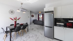 Una cocina moderna con refrigerador, mesa y sillas.