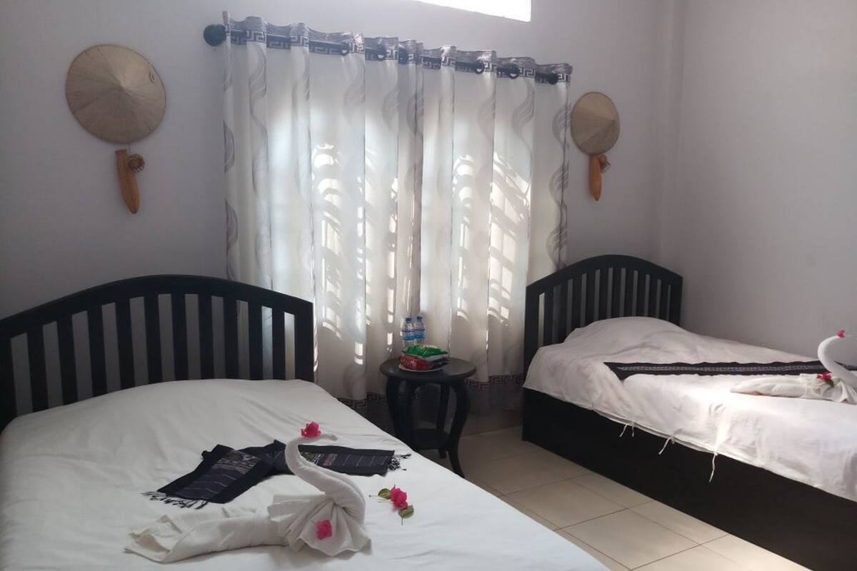 A hotel room with two beds, a small table with a water bottle, and a decorative wall hanging.