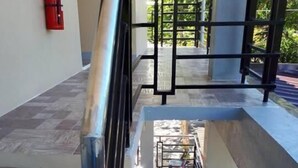 Eine Treppe mit Metallgeländern, ein Feuerlöscher an der Wand und Blick auf den Außenbereich mit Tisch und Stühlen.
