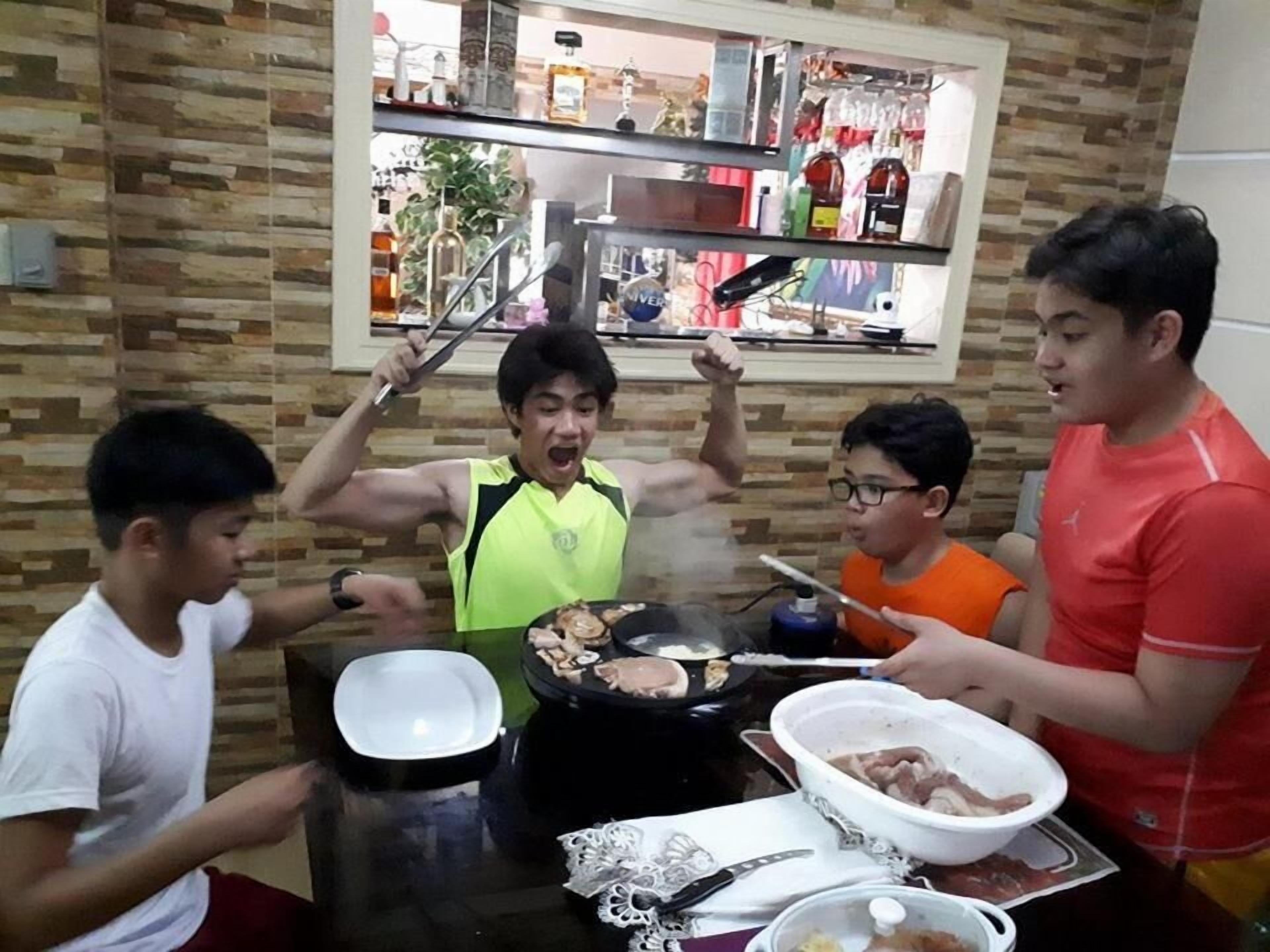 Un grupo de personas reunido alrededor de una mesa, cocinando comida con una estufa portátil.