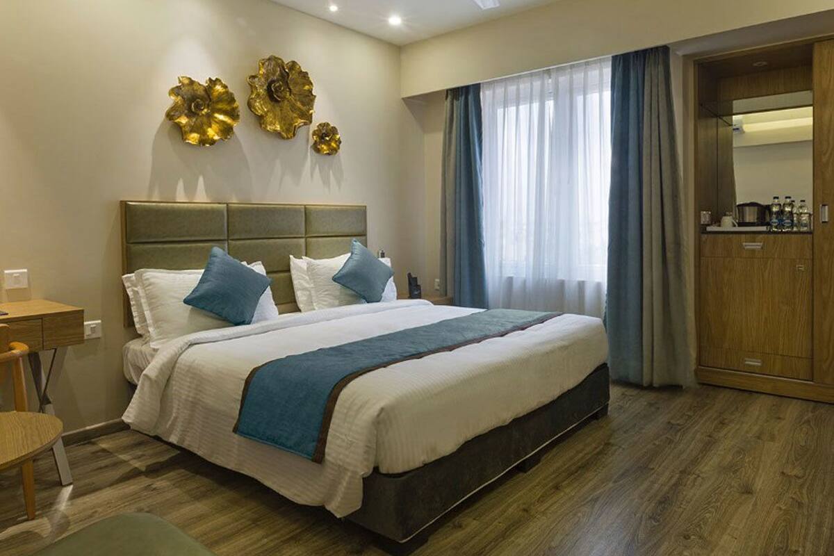 A hotel room with a large bed, a desk, a chair, a wardrobe, and a ceiling fan.
