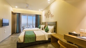 A hotel room with two beds, a desk, a chair, a flat-screen TV, and a view of the city. - Floressa Randa (Chennai)