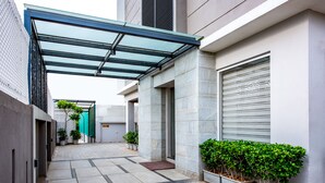 A modern building with a covered walkway, potted plants, and a garage door. - Floressa Randa (Chennai)