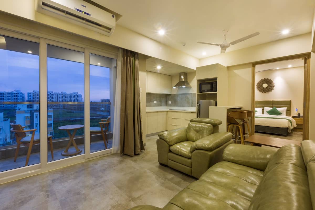 A modern apartment with a balcony, a dining area, a kitchen, and a living room with leather sofas.
