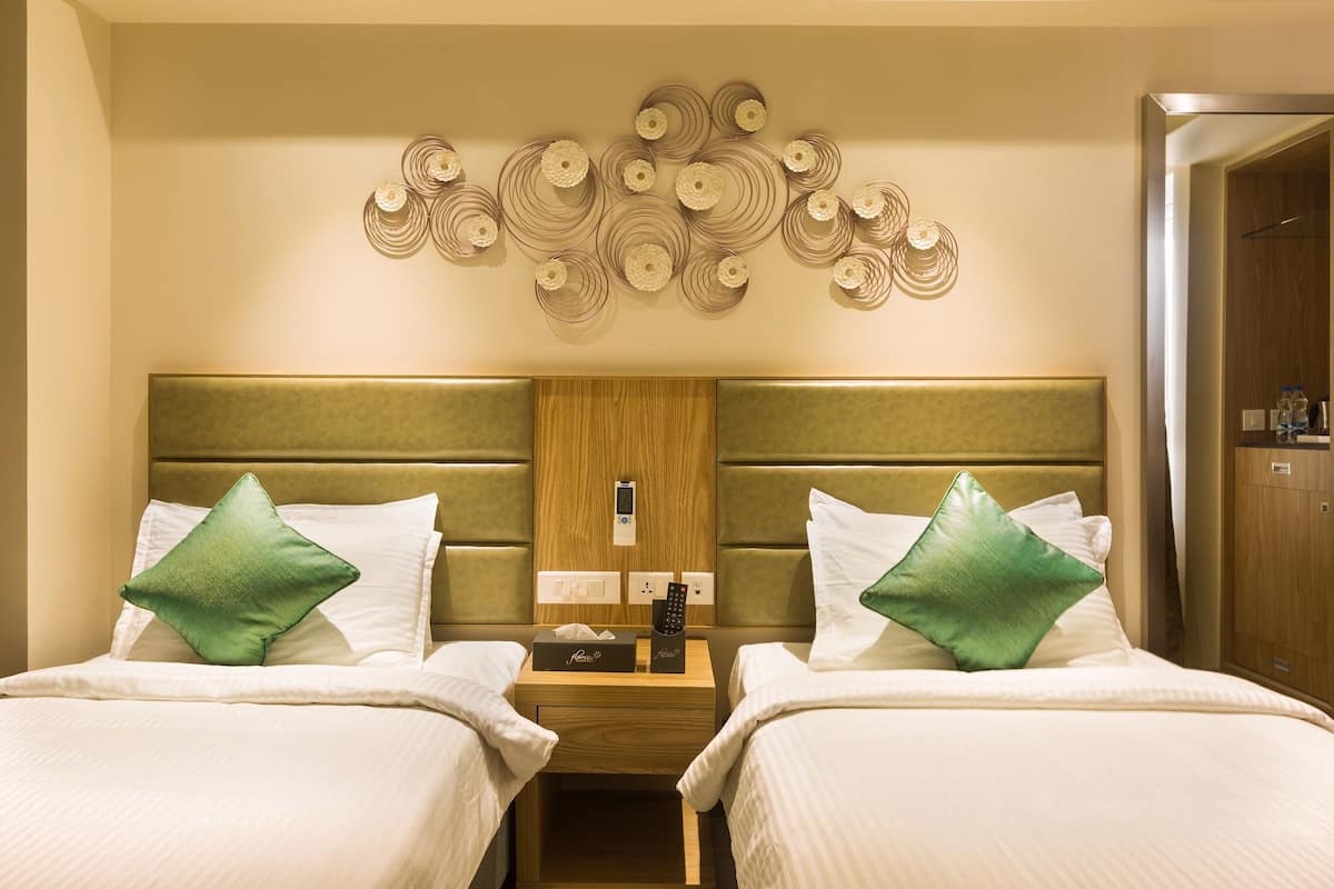 A hotel room with two beds, a nightstand, a wall art piece, and a wooden headboard.