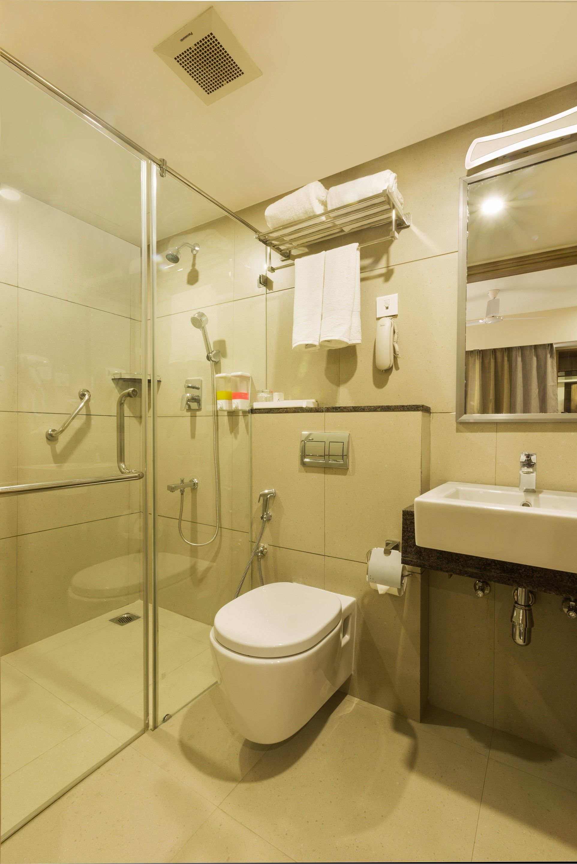 A modern bathroom with a glass-enclosed shower, a white toilet, and a sink with a mirror above it.