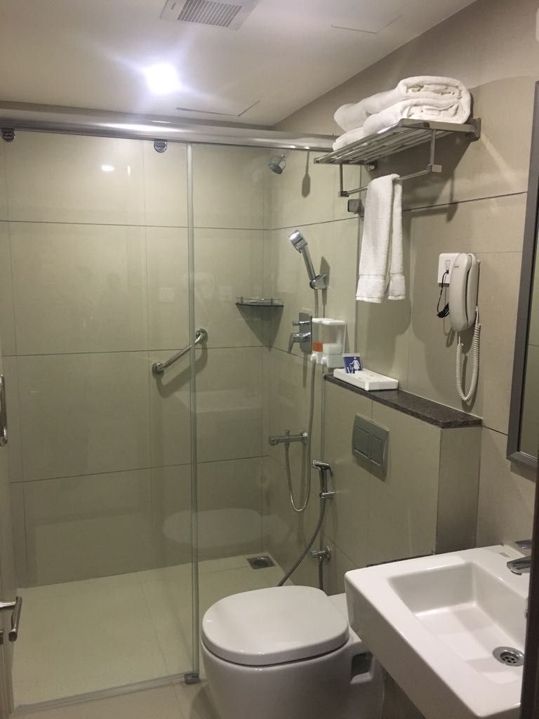 A modern bathroom with a glass-enclosed shower, a toilet, a sink, and a towel rack.