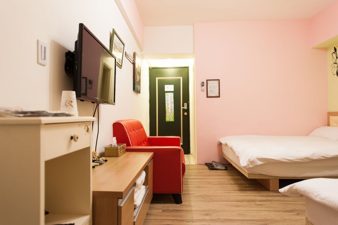 Una habitación de hotel con una cama, un escritorio con una silla, un televisor y una puerta.
