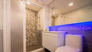 A bathroom with a glass-enclosed shower, a white toilet, and a vanity with a blue-lit countertop. - FengJia Pandola (Taichung)