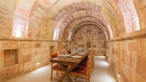 A long dining table set for a meal in a stone-walled room with arched ceilings. - Villa Estet Bag Oteli (Kula)