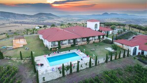 A large estate with a swimming pool, multiple red-roofed buildings, and a view of distant hills. - Villa Estet Bag Oteli (Kula)