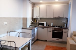 Efficient kitchenette with microwave, stove, and dishwasher, plus a dining area with table and chairs.