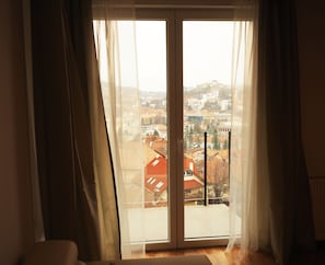 Enjoy breathtaking city views from the balcony, featuring a large sliding glass door and a comfortable chair.