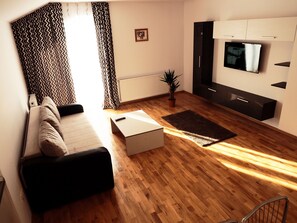 Relax in this inviting living room with a sofa set, flat-screen TV, and potted plant.