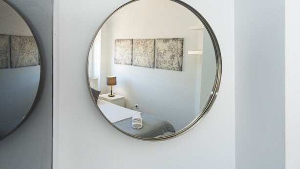 A bedroom with a round mirror, a bedside table with a lamp, and two wall-mounted paintings. - Central Lisbon Apartment near Príncipe Real & Avenida da Liberdade - TTL308 (Lisboa ciudad)