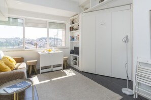 A modern living room with a sofa, a dining table with breakfast, a bookshelf, and a view of the city. - Central Lisbon Apartment near Príncipe Real & Avenida da Liberdade - TTL308 (Lisboa ciudad)