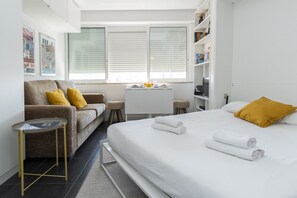 A hotel room with a bed, a sofa, a small table, and a desk with a chair.