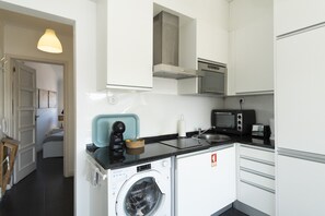 Eine kleine Küche mit Waschmaschine, Mikrowelle und Toaster.