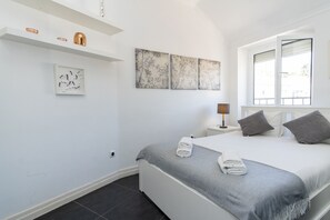 Ein Schlafzimmer mit einem Bett, einem Nachttisch, einer Lampe und Bildern an der Wand.