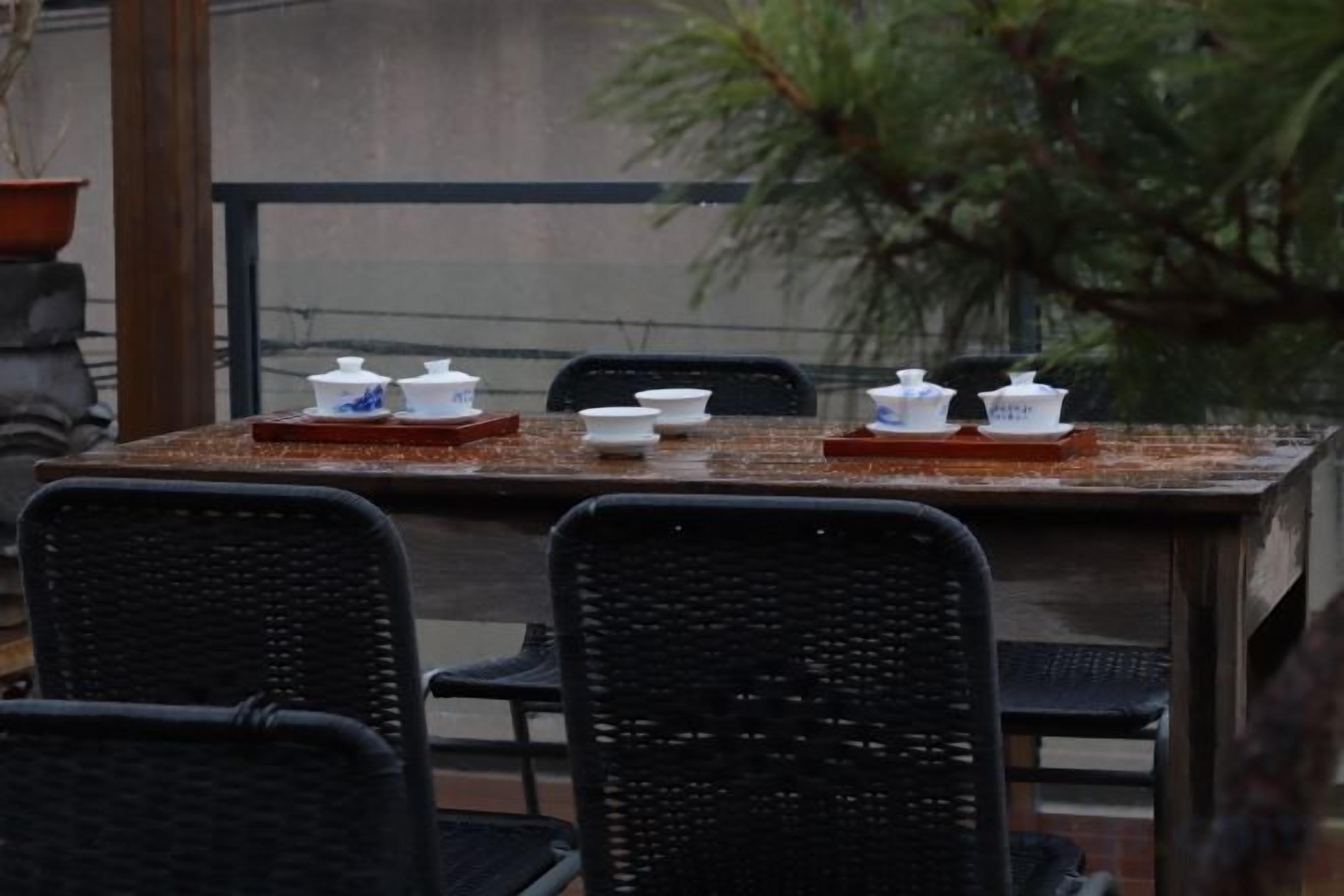 Une table à manger avec de la vaisselle blanche et un plateau, entourée de chaises noires.