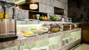 A buffet area with marble countertops, a beverage dispenser, and various food items. - Conifer Grand Hotel (Hanoi)