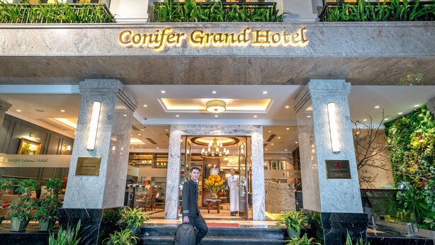 The Conifer Grand Hotel entrance with marble columns, a grand staircase, and lush greenery. - Conifer Grand Hotel (Hanoi)