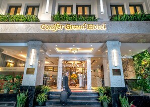 The Conifer Grand Hotel entrance with marble columns, a grand staircase, and lush greenery. - Conifer Grand Hotel (Hanoi)