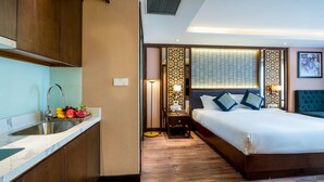 A hotel room with a bed, a nightstand, a lamp, a sink, and a fruit bowl. - Conifer Grand Hotel (Hanoi)