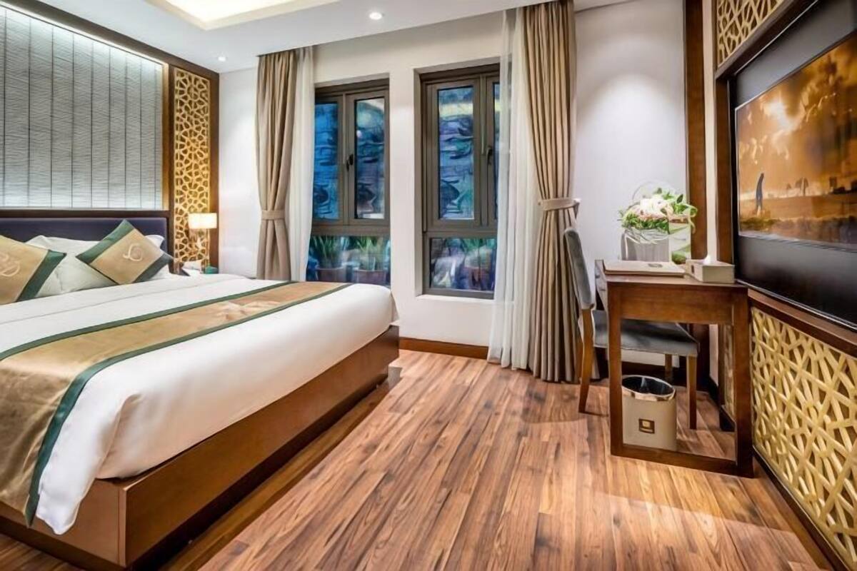 A hotel room with a large bed, a desk, and a TV.