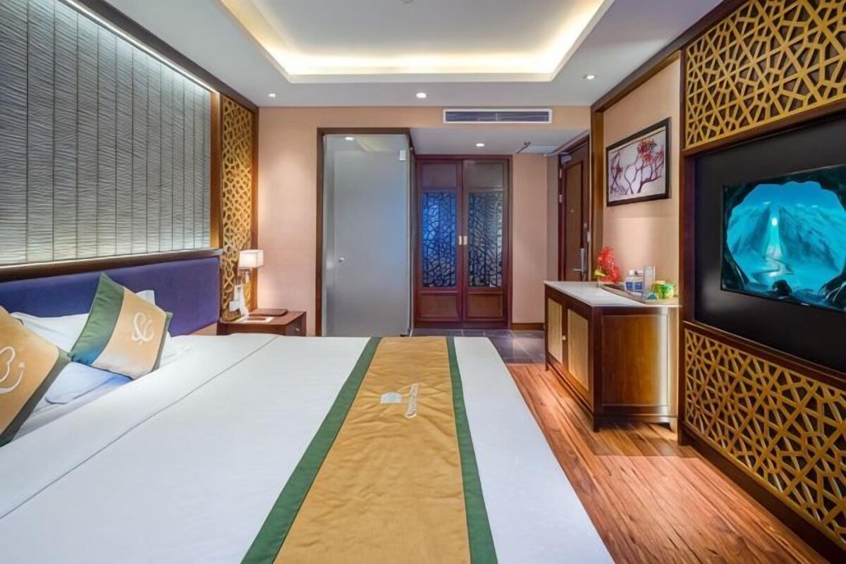 A hotel room with a bed, a desk, a TV, and a door leading to a bathroom.