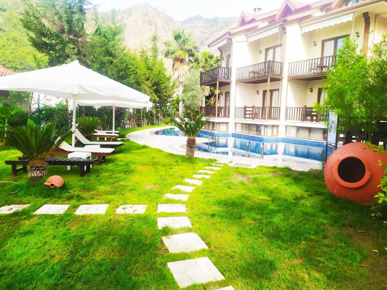 Un hotel con piscina, sillas de descanso al aire libre y un camino de jardín.
