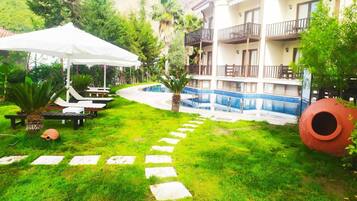 Un hotel con piscina, sillas de descanso al aire libre y un camino de jardín.