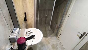 Un baño con lavamanos blanco, espejo y cabina de ducha.