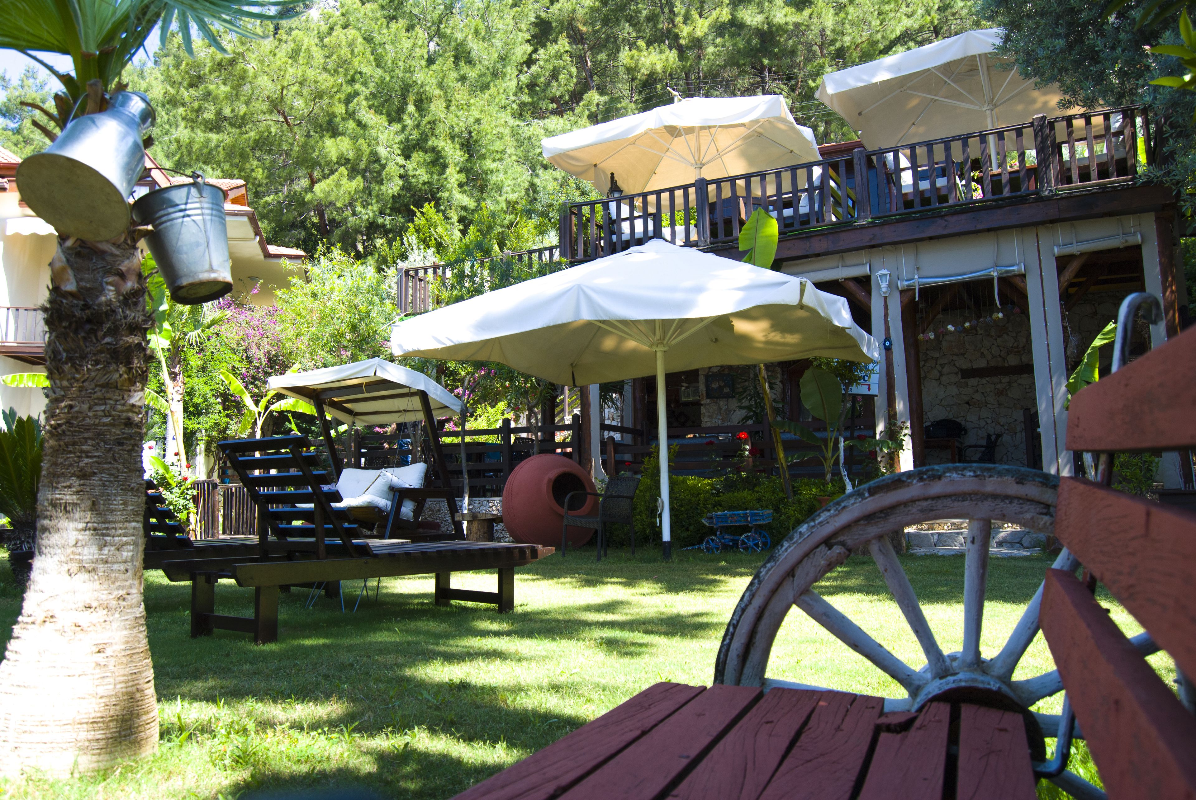 Un espace patio aménagé avec des sièges d’extérieur, des parasols et une table en bois.
