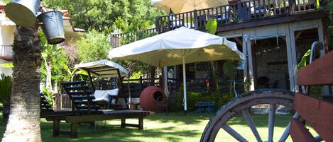 Un espace patio aménagé avec des sièges d’extérieur, des parasols et une table en bois.