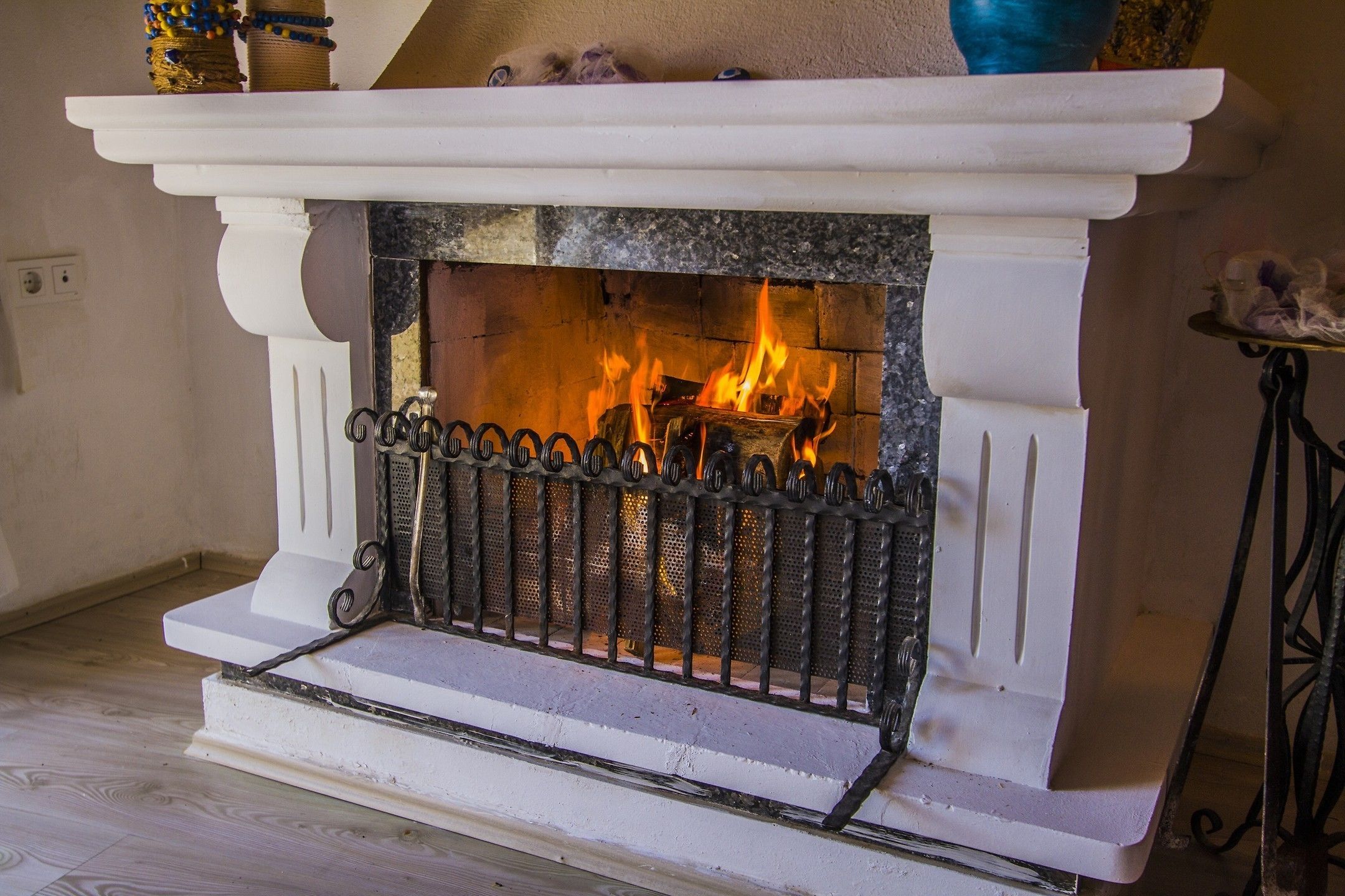 A fireplace with a white mantel and a metal screen.