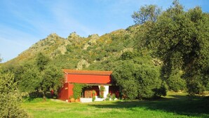 A red-roofed building with a white facade, surrounded by lush greenery and a mountainous backdrop. - Really special holiday barn  in beautiful sierra scenery with great pool  (Caceres)