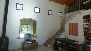 A spacious living room with a wooden staircase, a fireplace, a television, and a bookshelf. - Really special holiday barn  in beautiful sierra scenery with great pool  (Caceres)