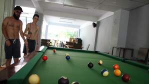 Una mesa de billar con bolas y dos personas a su lado.