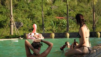 A pool area with people relaxing and sitting by the poolside.